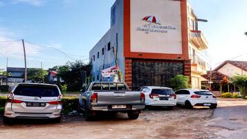 A building with a sign reading "d'Akouloua Residence" and several parked vehicles in front.