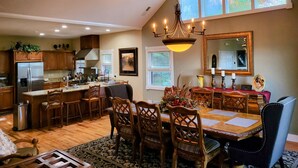 A spacious kitchen with wooden cabinets, a stainless steel refrigerator, and a dining area with a wooden table and chairs. - 4 Bedroom + 4 Bathroom Mountain Home at 4,700ft Views of Blue Ridge Mts + Big Bald + Spa + Elevator (Mars Hill)