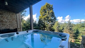 A hot tub with a stone wall and a view of trees and mountains. - 4 Bedroom + 4 Bathroom Mountain Home at 4,700ft Views of Blue Ridge Mts + Big Bald + Spa + Elevator (Mars Hill)