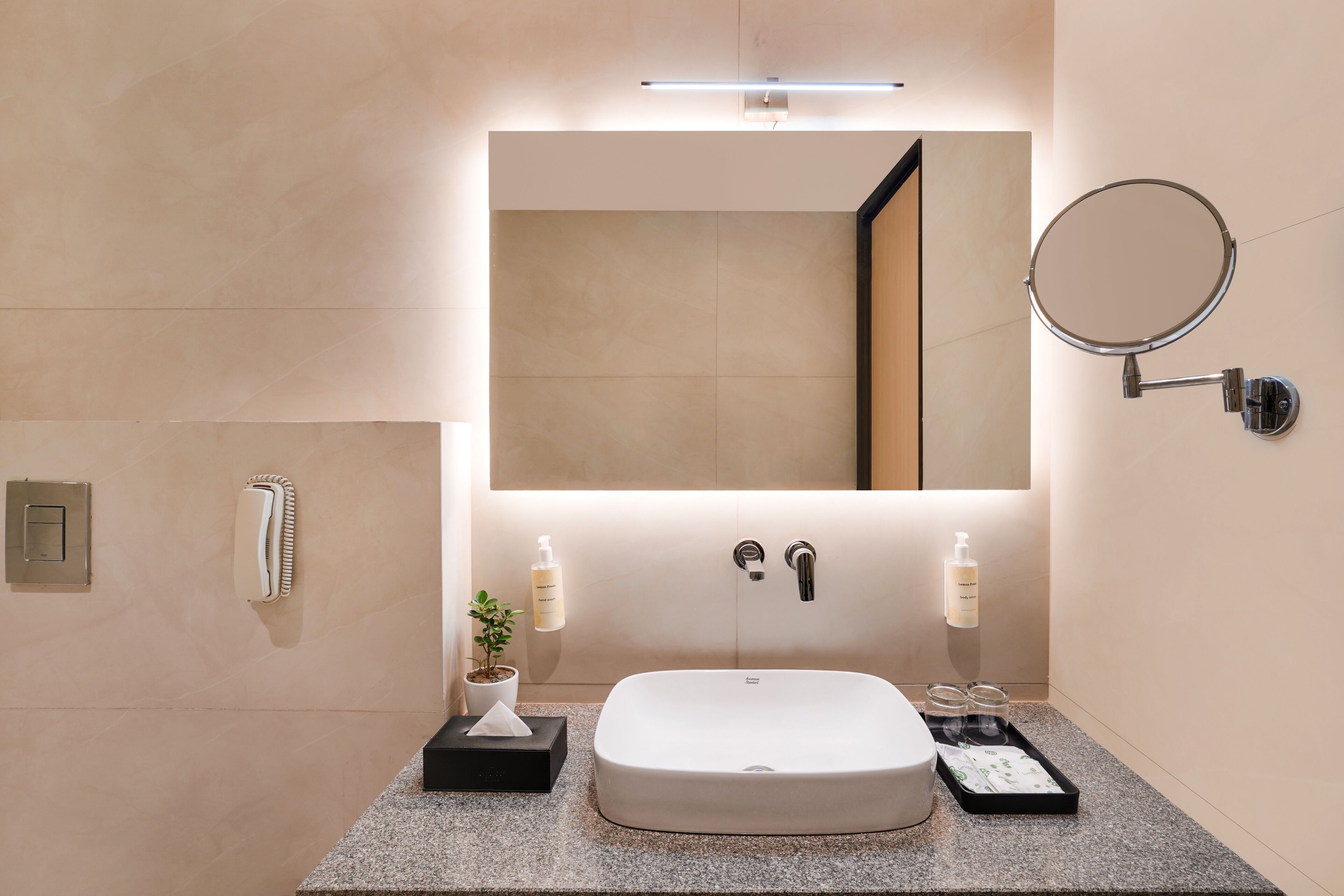 A modern bathroom with a large mirror, a white sink, and a round mirror on the wall.