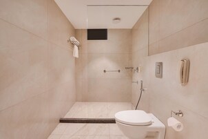 Un baño moderno con ducha, inodoro y perchero para toallas.