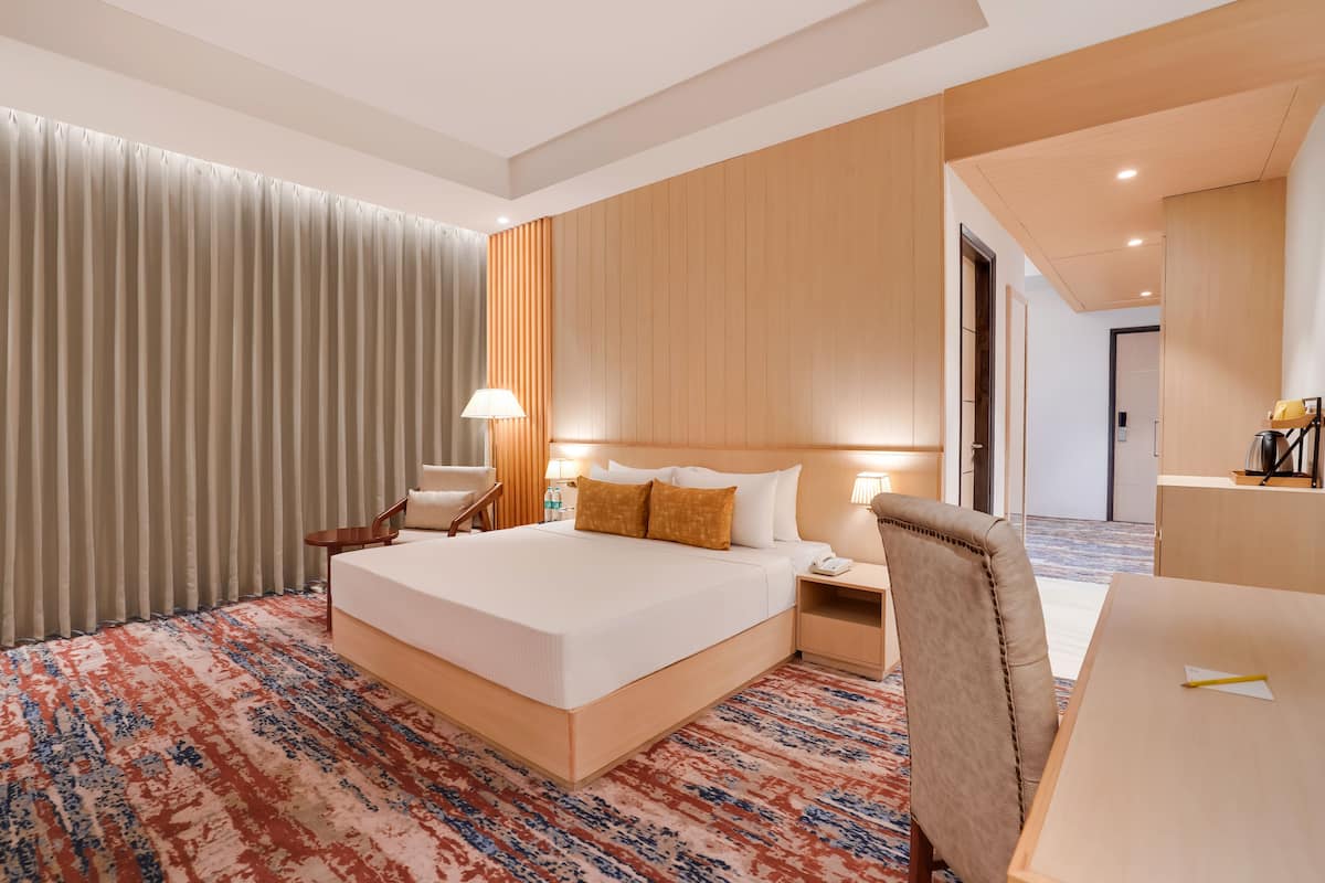 A hotel room with a large bed, bedside tables, a desk, and a chair.