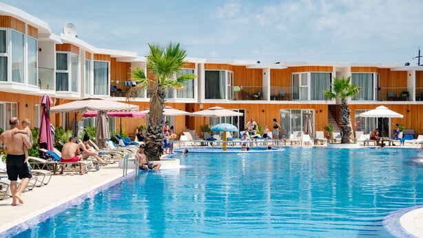 A hotel pool area with sun loungers, umbrellas, and a clear blue pool.