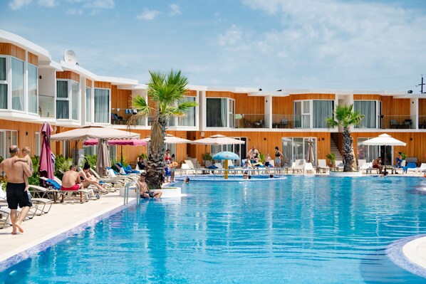 A hotel pool area with sun loungers, umbrellas, and a clear blue pool.