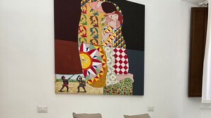 A bedroom with a bed, pillows, a bedside table with a lamp, and a wall painting.
