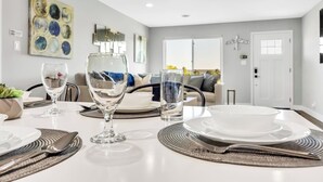 A dining area with a table set for two, including wine glasses, plates, and cutlery. - Modern&Comfy|EV Charger|Kids&Pets| quick 80 access (Auburn)