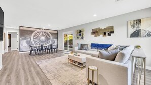 A spacious living area with a modern sofa, a dining table with chairs, and a large abstract painting on the wall. - Modern&Comfy|EV Charger|Kids&Pets| quick 80 access (Auburn)