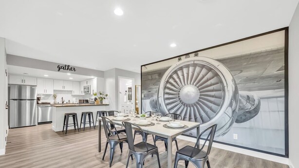 A modern kitchen with white cabinets, stainless steel appliances, and a dining area with a large table and chairs. - Modern&Comfy|EV Charger|Kids&Pets| quick 80 access (Auburn)