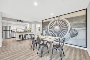 A modern kitchen with white cabinets, stainless steel appliances, and a dining area with a large table and chairs. - Modern&Comfy|EV Charger|Kids&Pets| quick 80 access (Auburn)