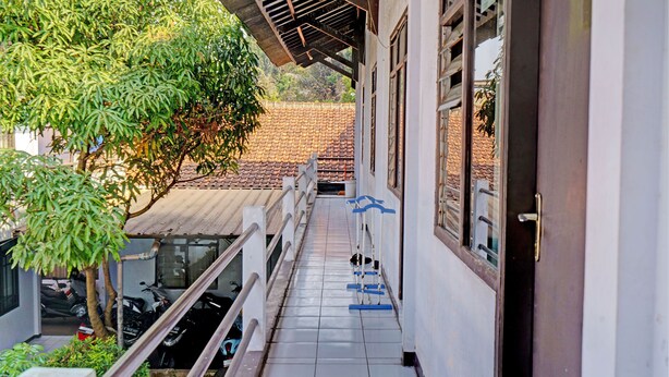 Un balcon étroit doté d’un sol carrelé, d’une balustrade et offrant une vue sur un immeuble dont le toit est également recouvert de tuiles.
