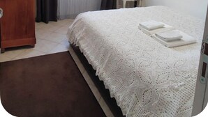 Un dormitorio con una cama, un aparador de madera, una silla y una mesita de noche.