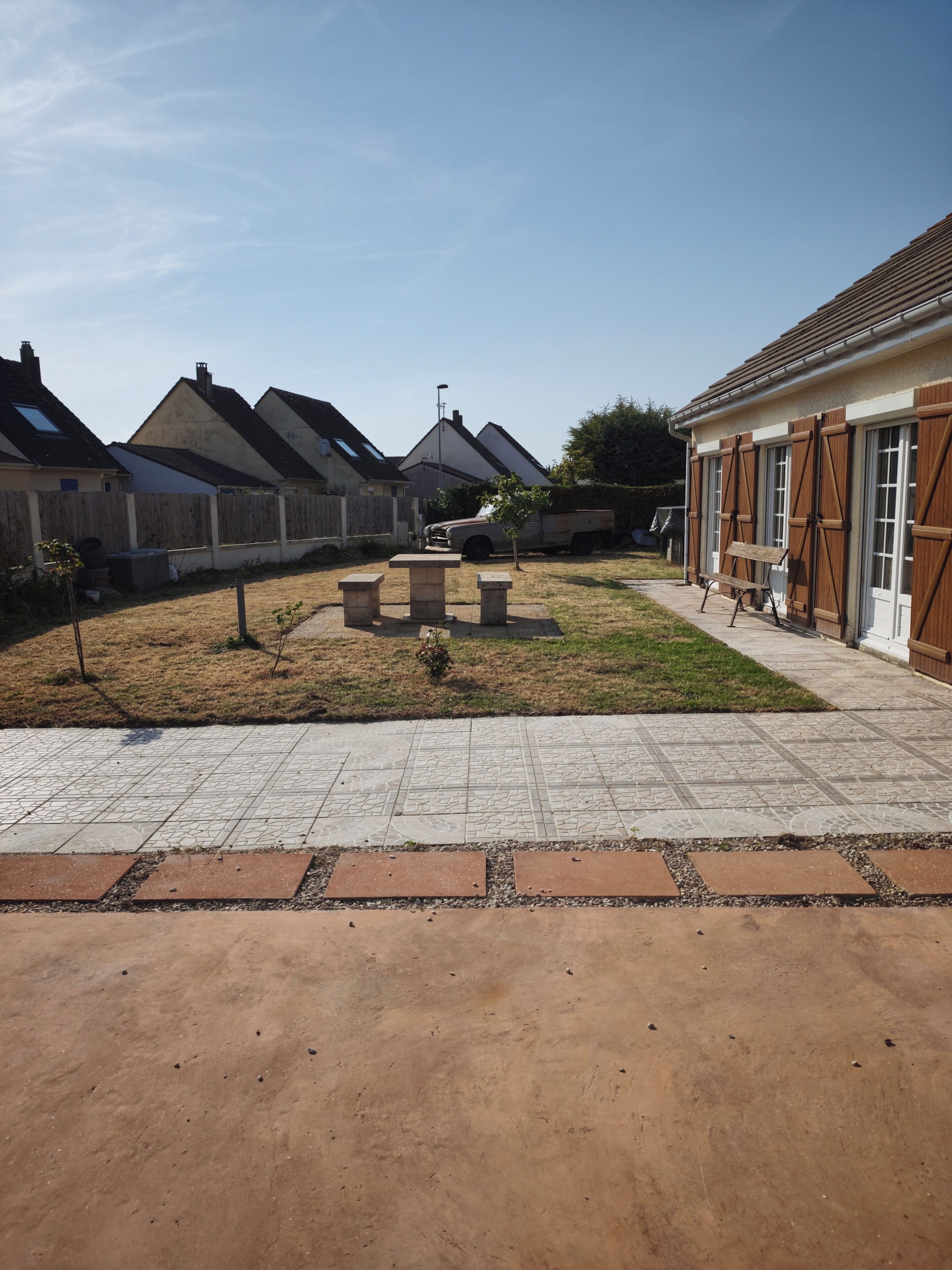 A residential area with houses, a paved walkway, and a picnic table.