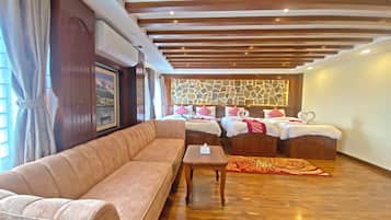 A hotel room with a sofa, two beds, a stone wall, and a wooden ceiling.