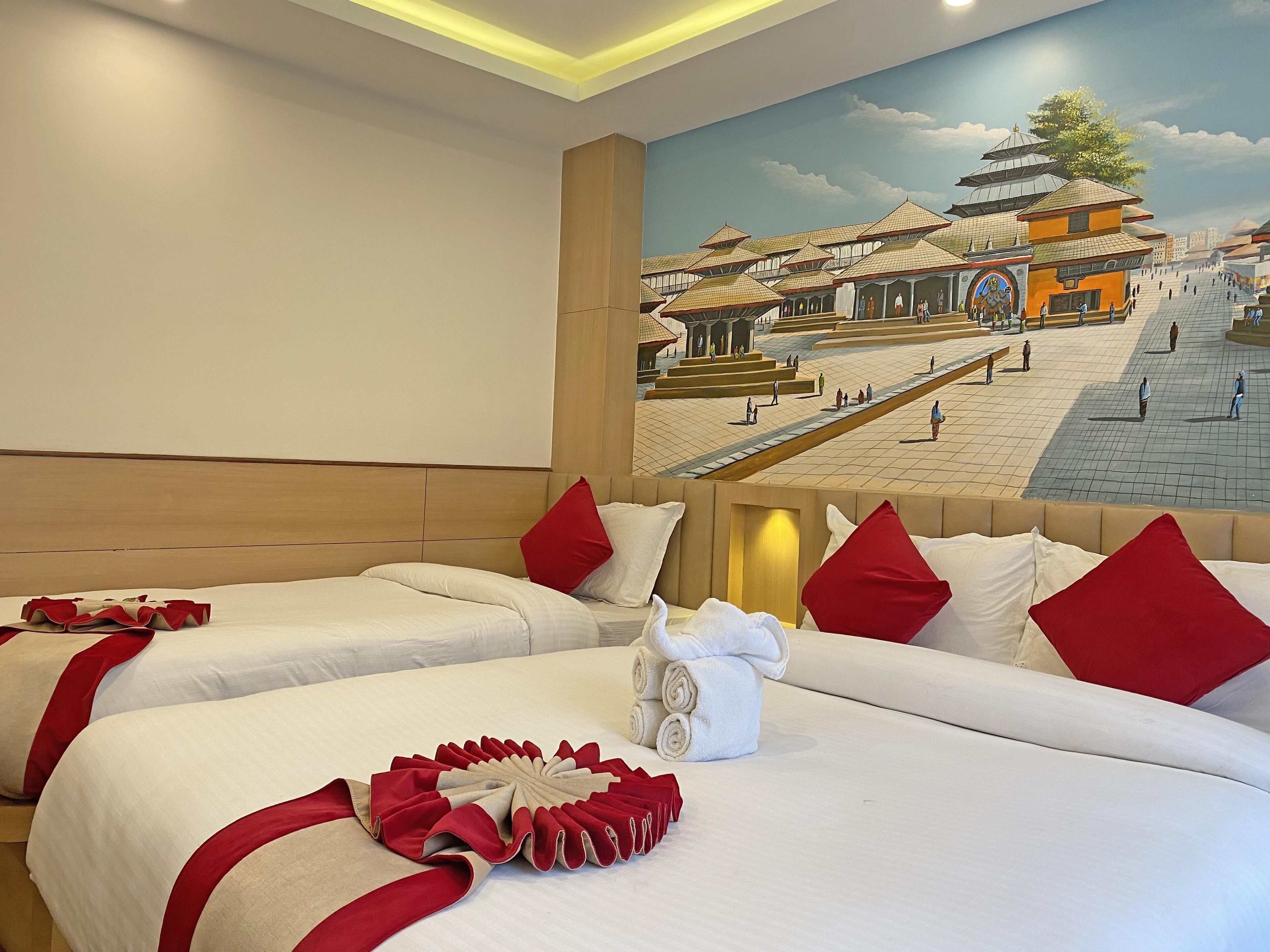 Habitación de hotel con dos camas, ropa de cama roja y blanca, y un mural de una construcción tradicional.