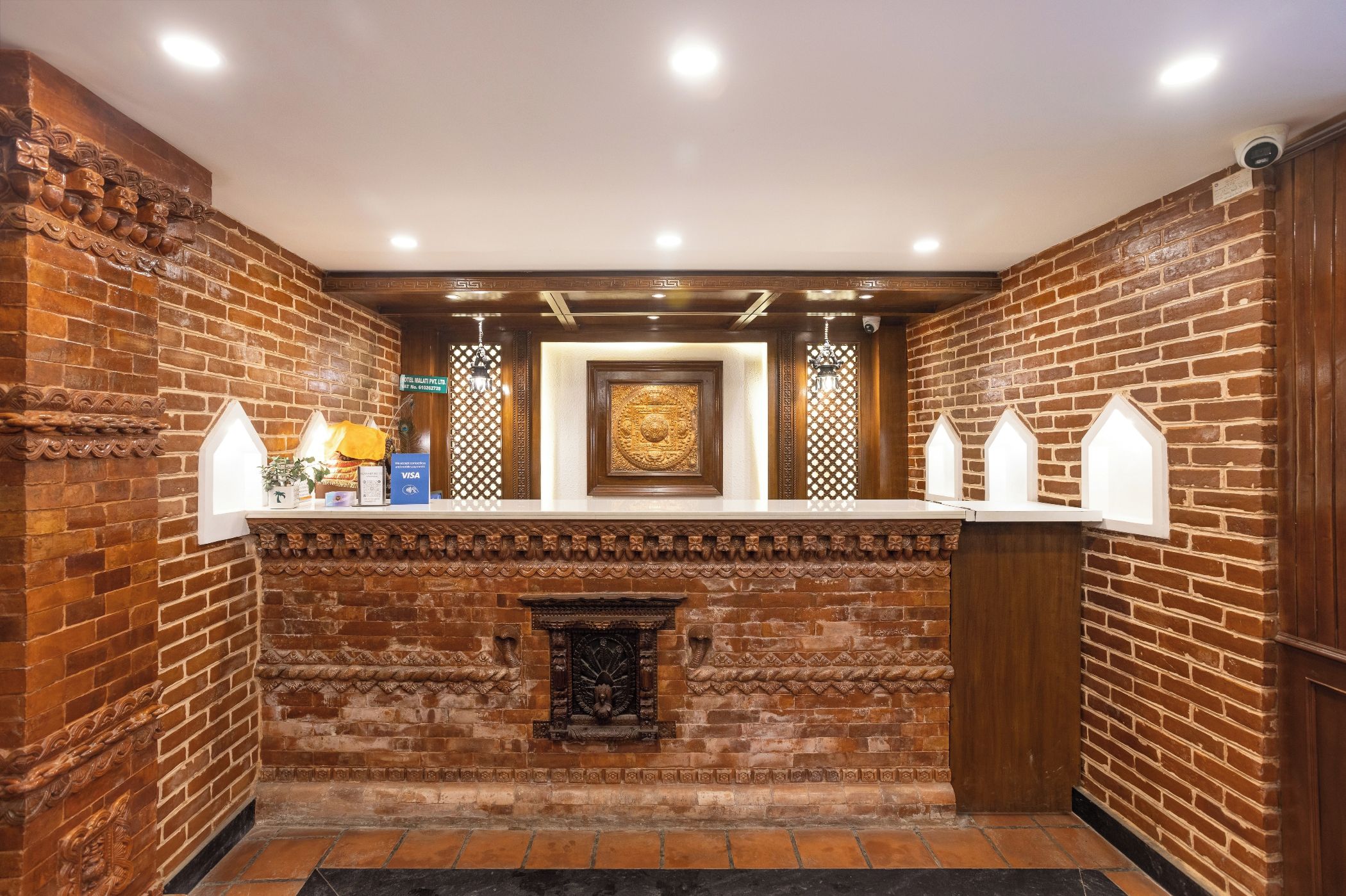 Un área de recepción con pared de ladrillo, mostrador de recepción y chimenea decorativa.
