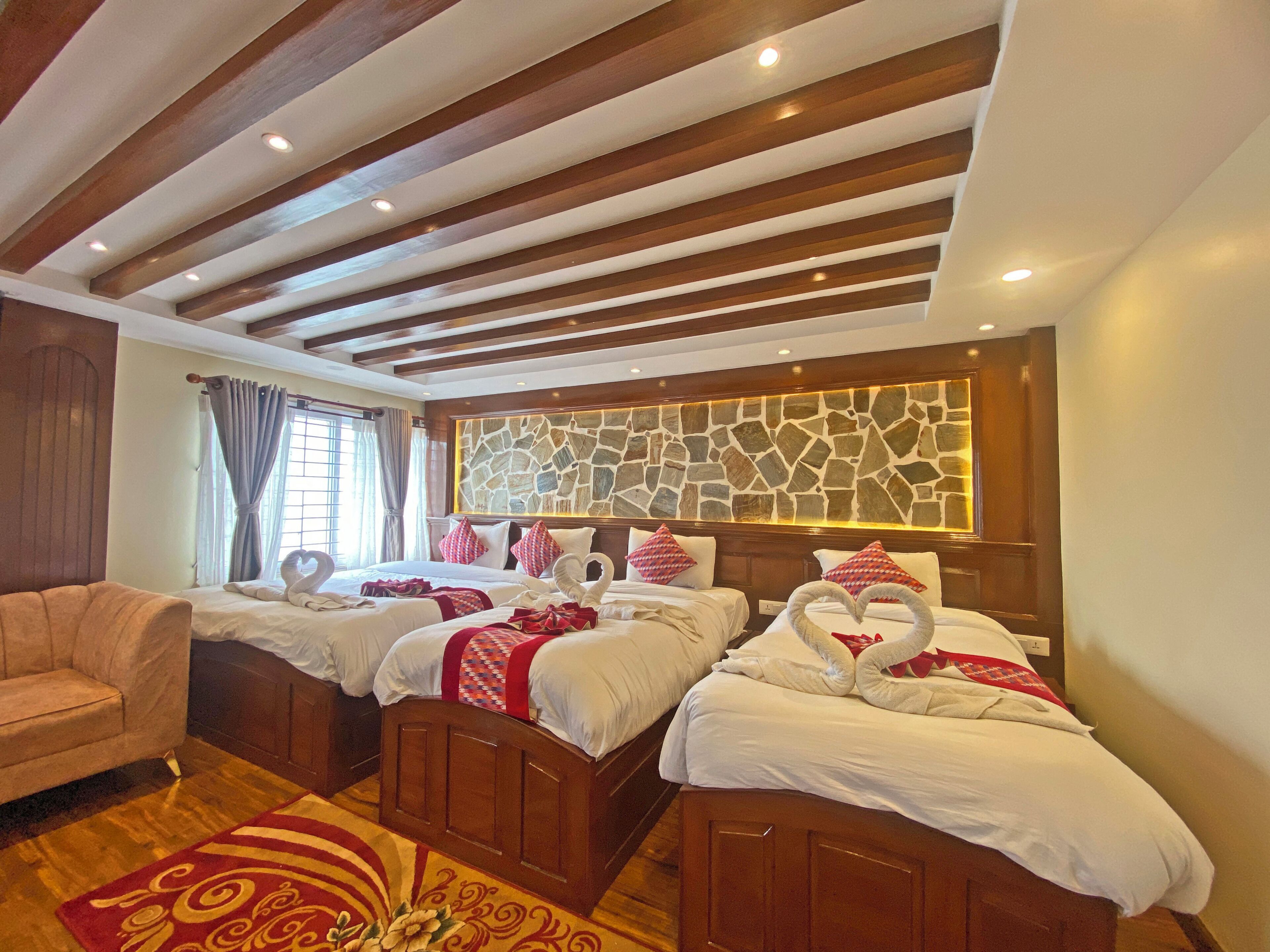 Une chambre d’hôtel avec deux lits, un plafond en bois, un mur en pierre et un tapis rouge à motifs.