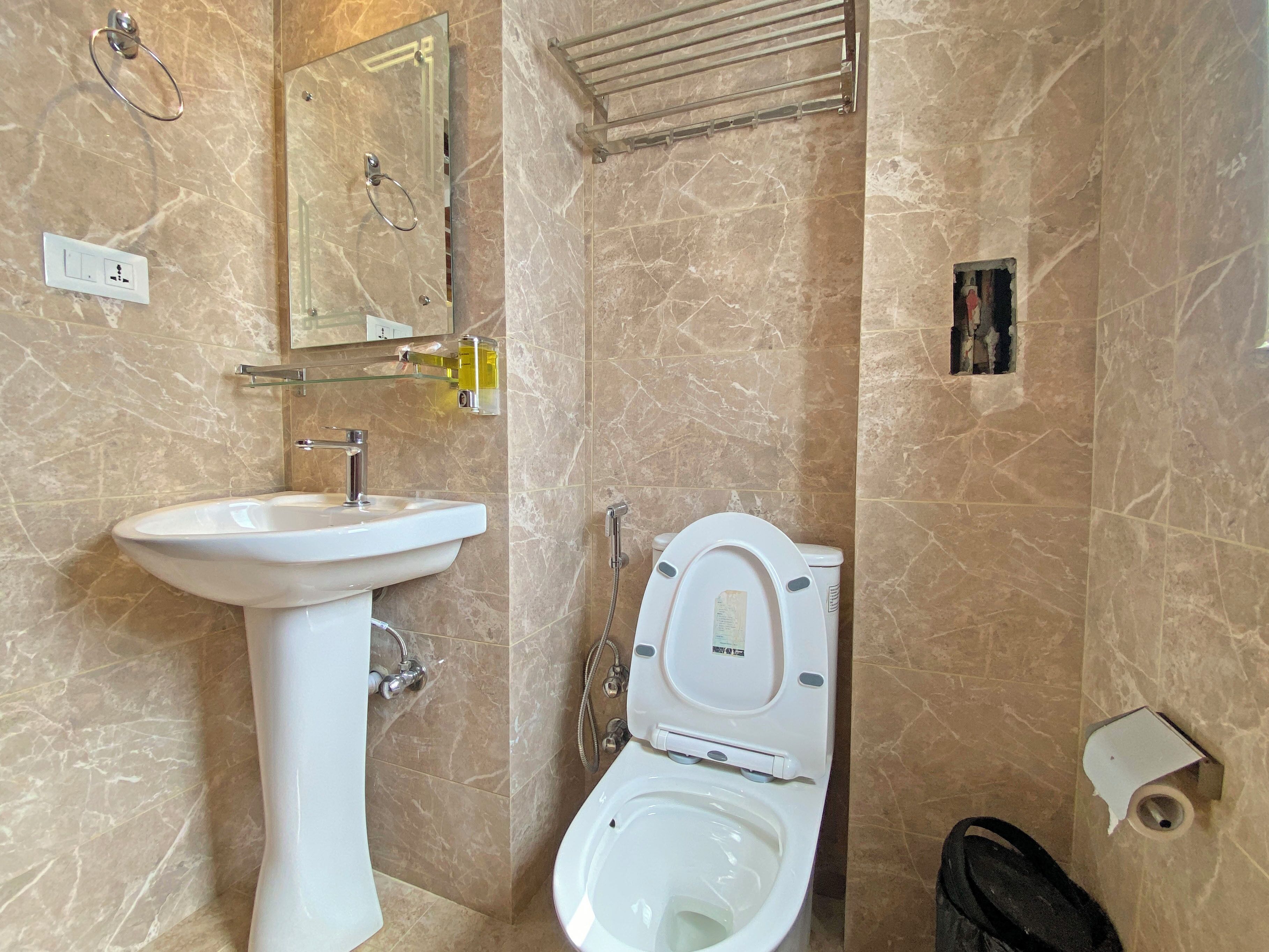 Un baño con lavamanos pedestal, inodoro y un perchero para toallas.