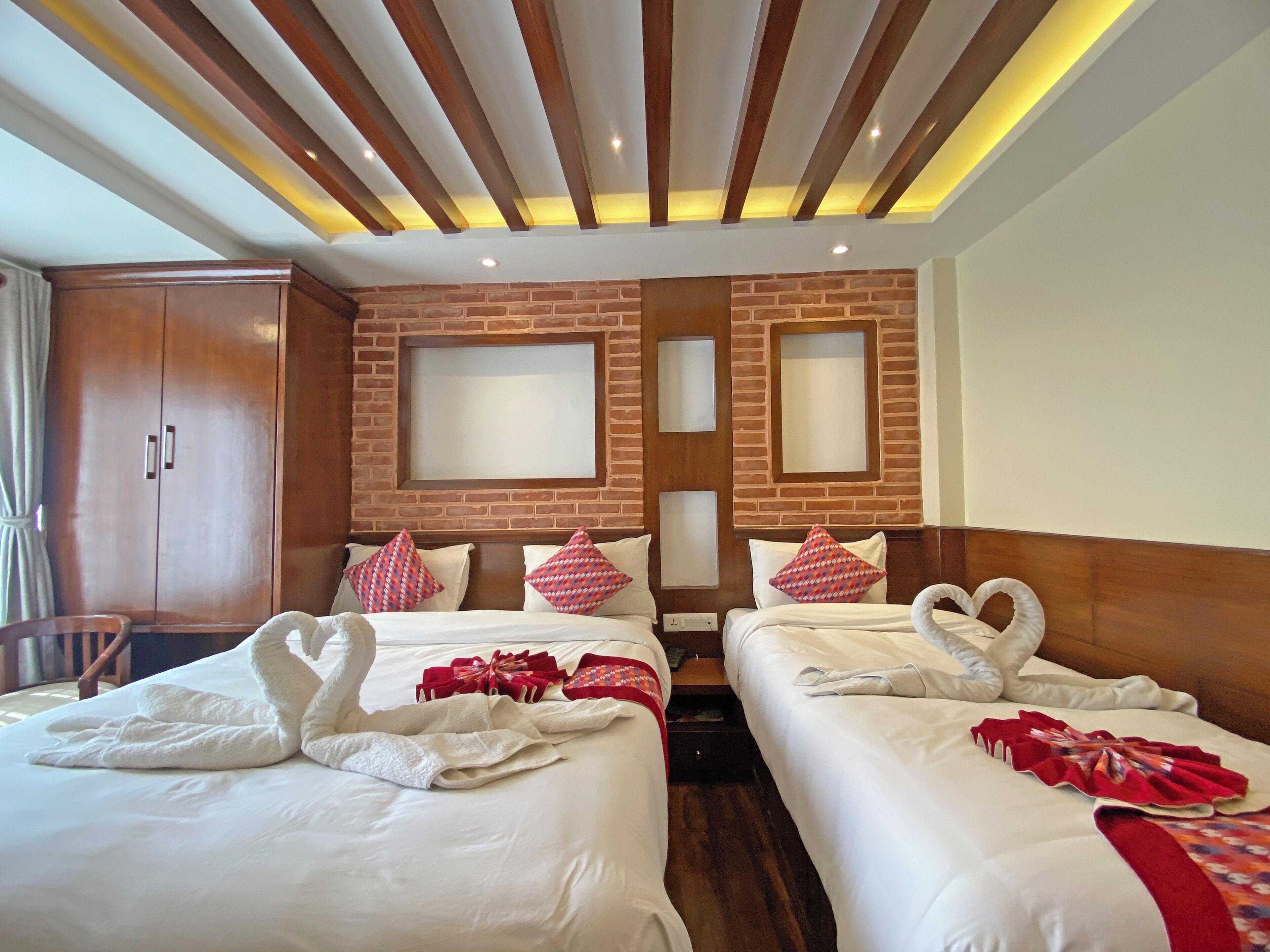 Una habitación de hotel con dos camas, un armario de madera y una pared decorativa de ladrillo.