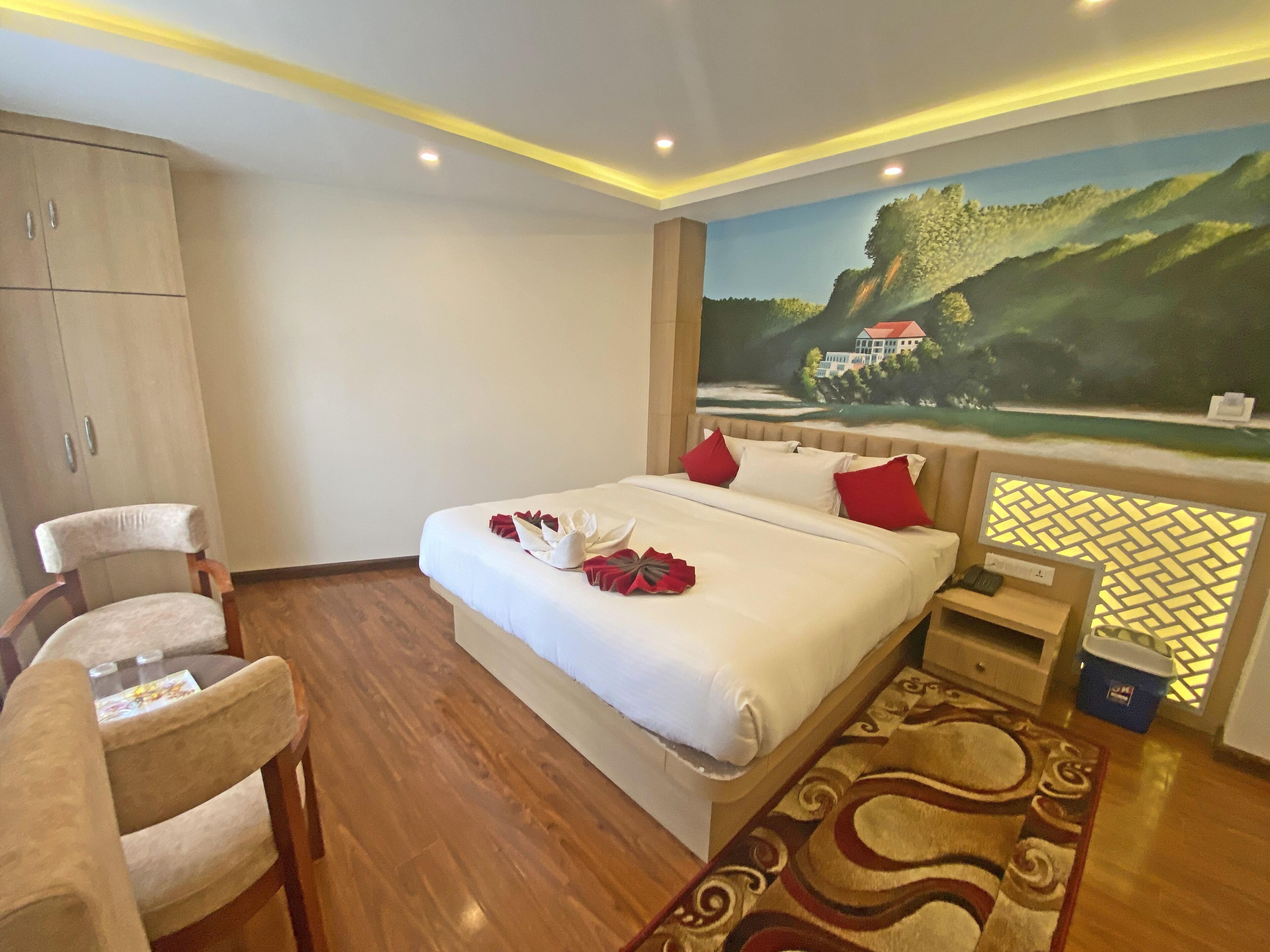 Habitación de hotel con cama, escritorio, silla, armario y un cuadro de un paisaje.