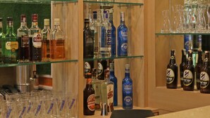 Zona de bar con estantes llenos de botellas de licor y vasos.