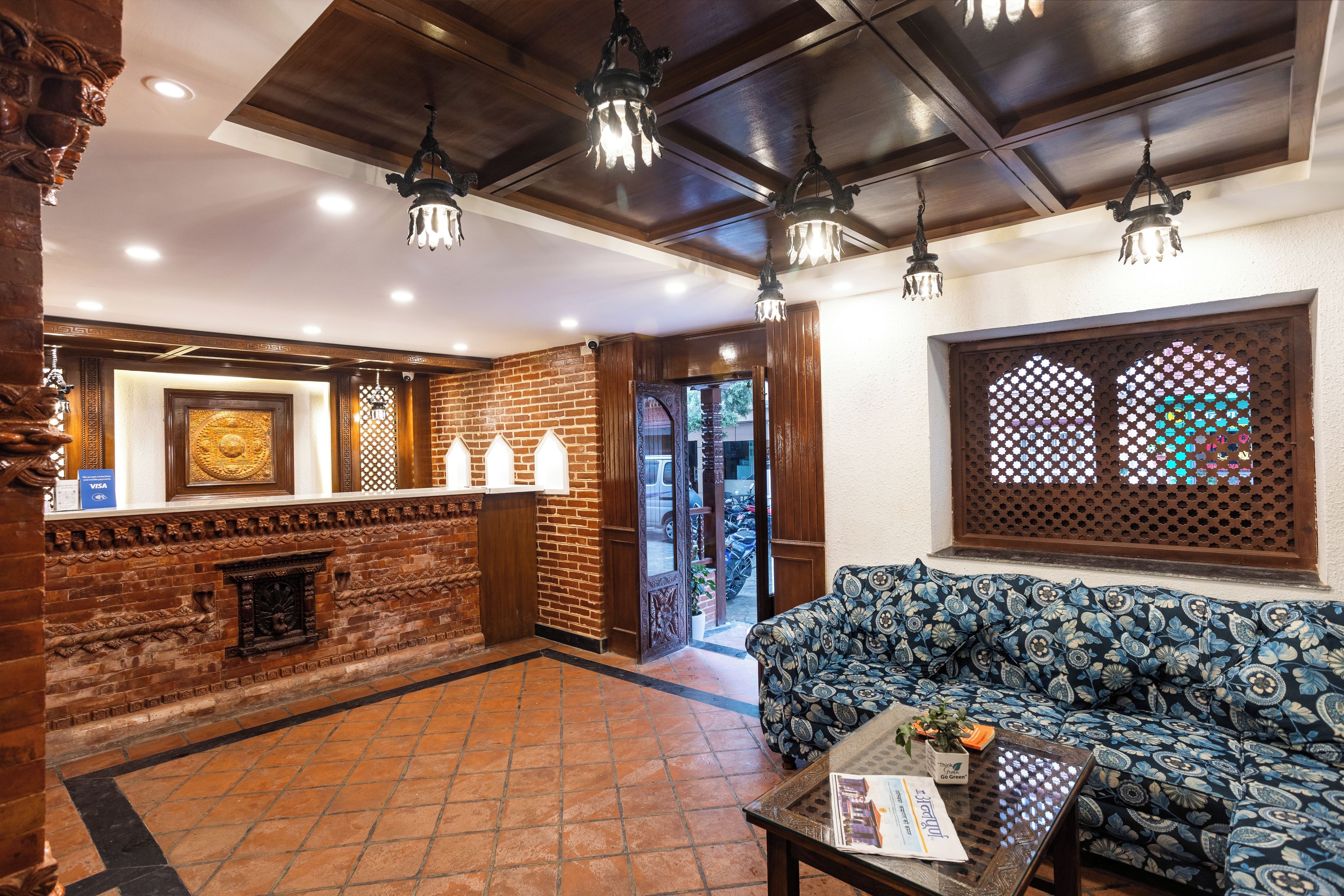 A lobby with a brick wall, a reception desk, a sofa, and a patterned table.