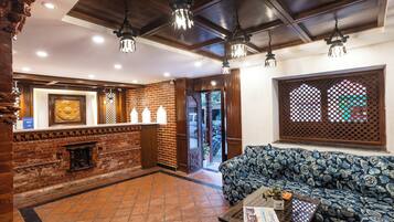 A lobby with a brick wall, a reception desk, a sofa, and a patterned table.