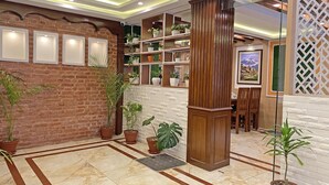 A lobby with a brick wall, potted plants, a wooden column, and a tiled floor. - Hotel Malati (Kathmandu)