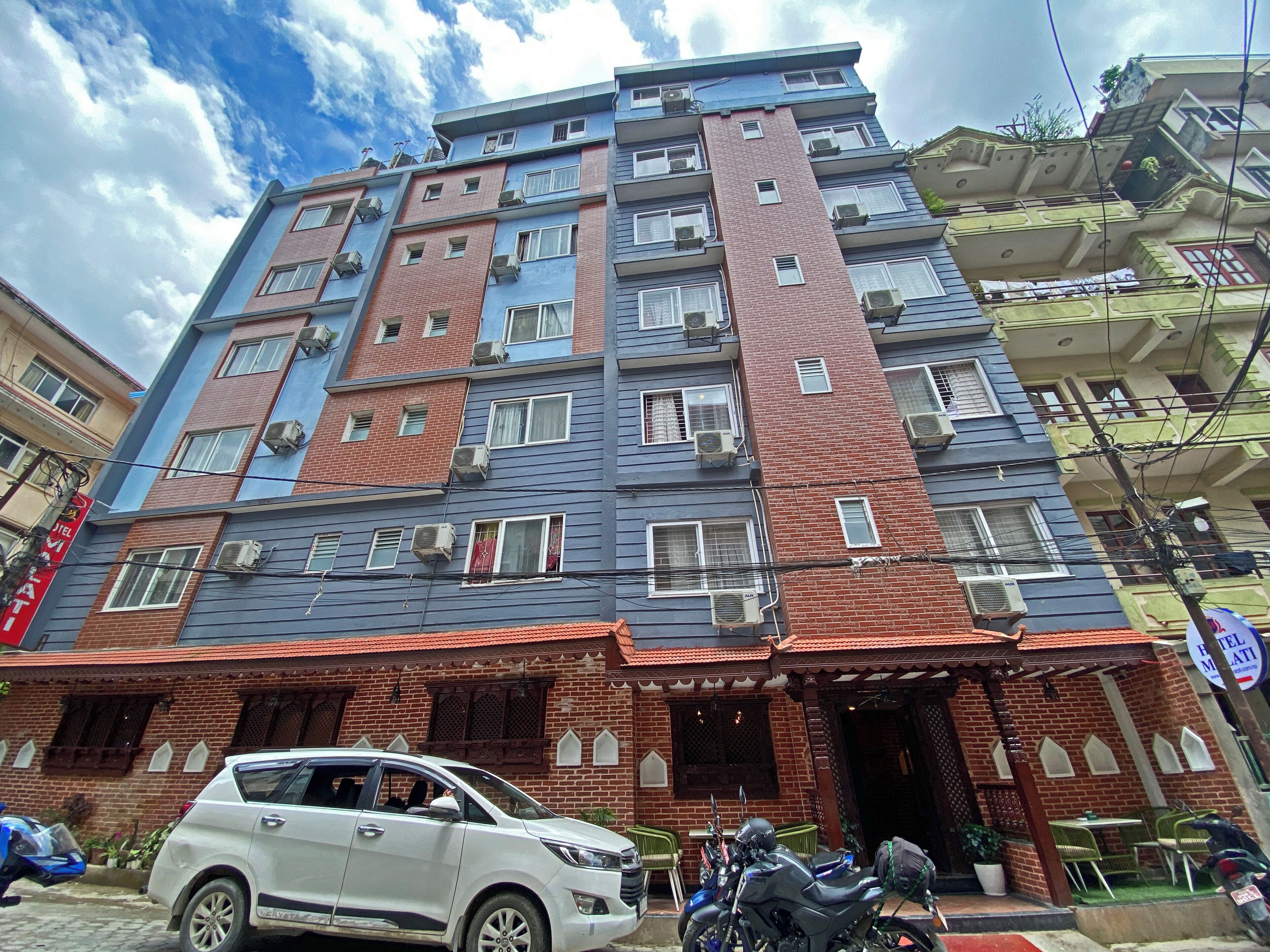 Un edificio a più piani con facciate in mattoni e dipinte, numerosi balconi e un ingresso a livello strada con portico.