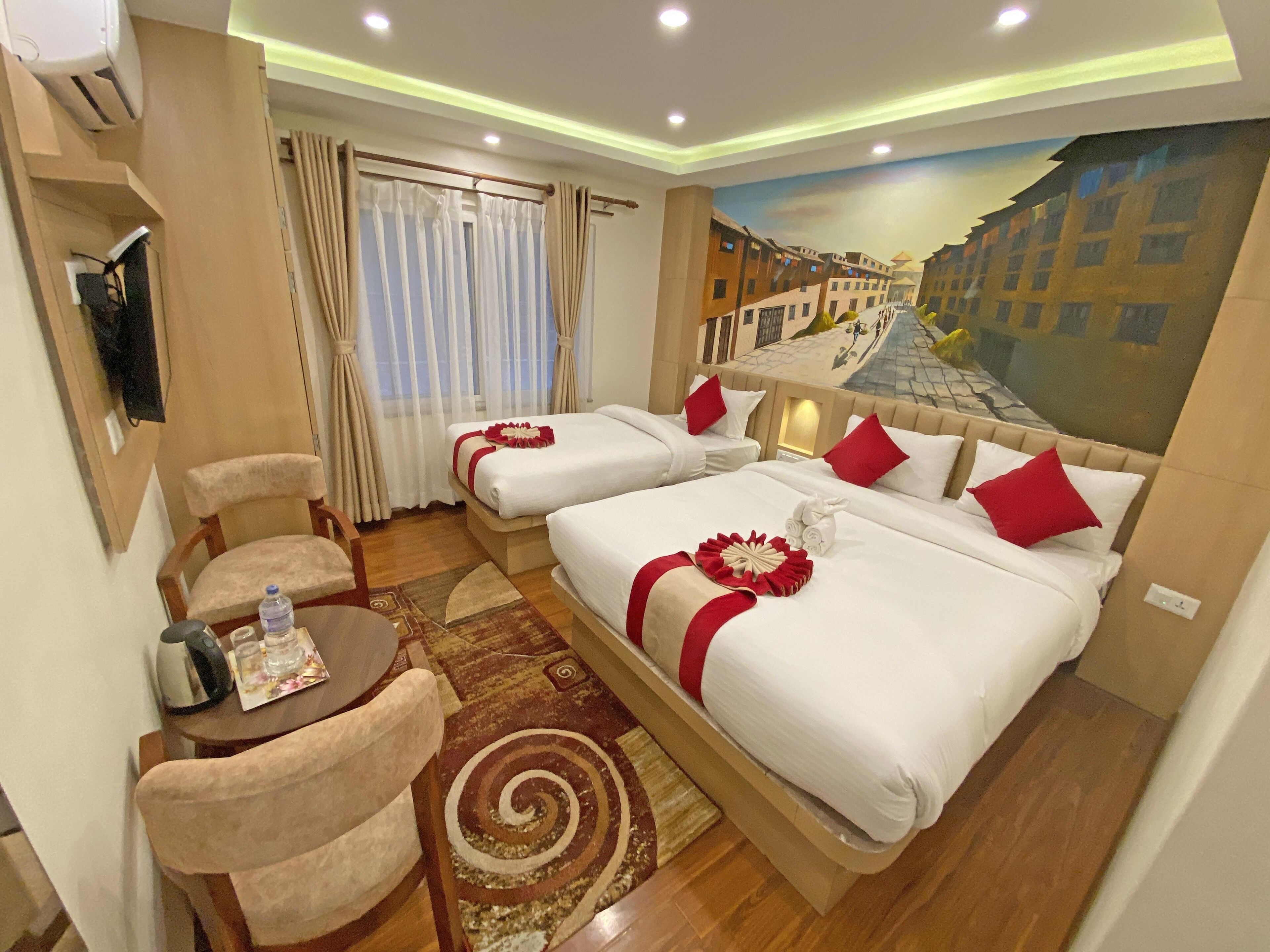 Une chambre d’hôtel avec deux lits, un bureau, une chaise, une bouteille d’eau et un tableau représentant un paysage urbain.
