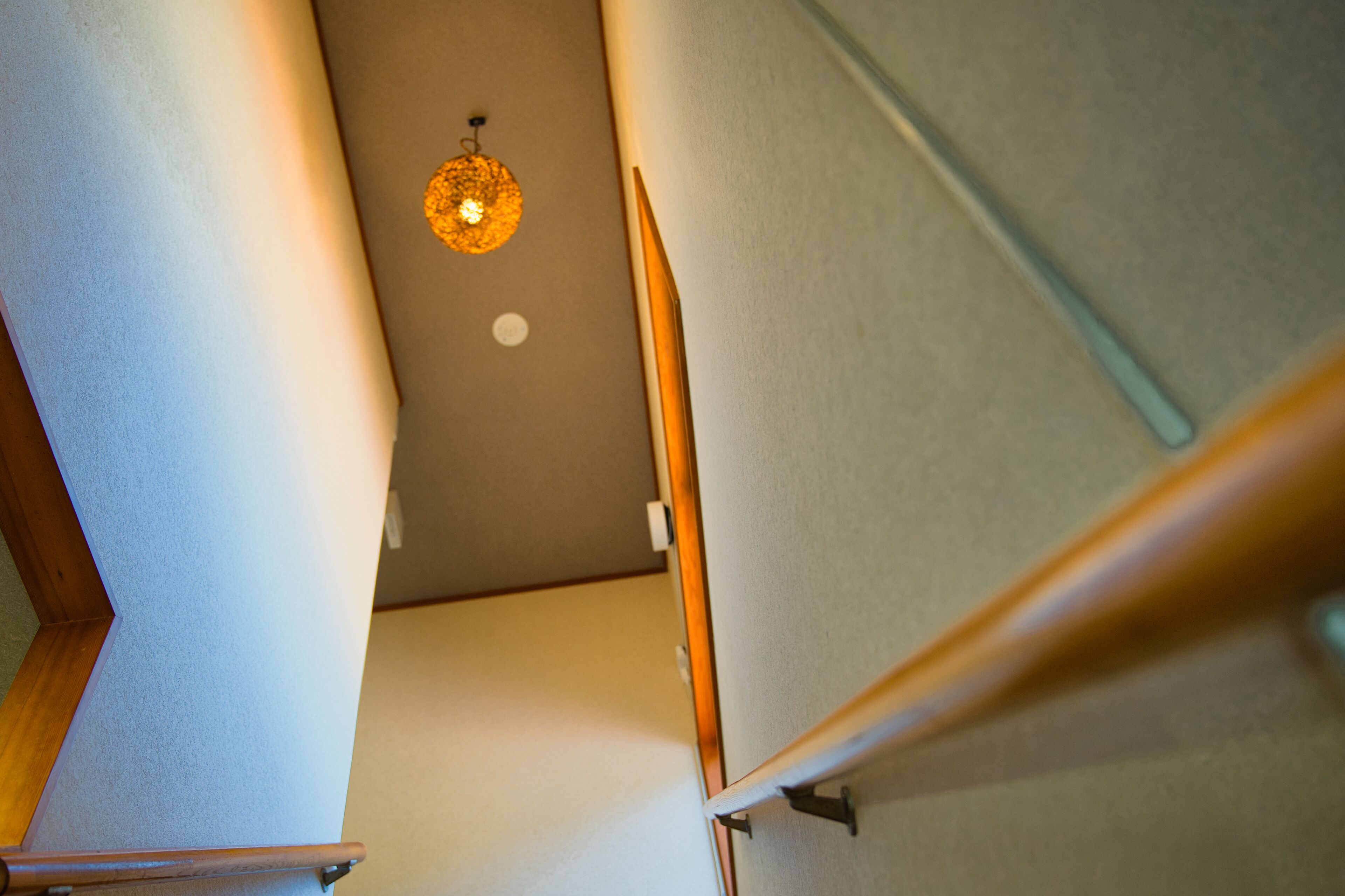 A staircase with a wooden handrail and a light fixture on the ceiling.