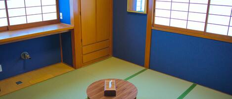 A tatami mat room with a wooden table, a wardrobe, and a window with a grid pattern.