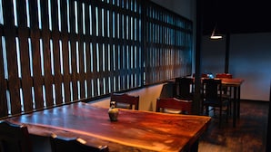 Una mesa de comedor de madera con sillas, un jarrón y una pared con listones verticales.