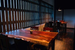 Una mesa de comedor de madera con sillas, un jarrón y una pared con listones verticales.