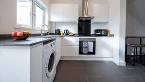 A compact kitchen with a washing machine, a microwave, and a coffee maker. - Durham View by Tŷ SA (Newport)