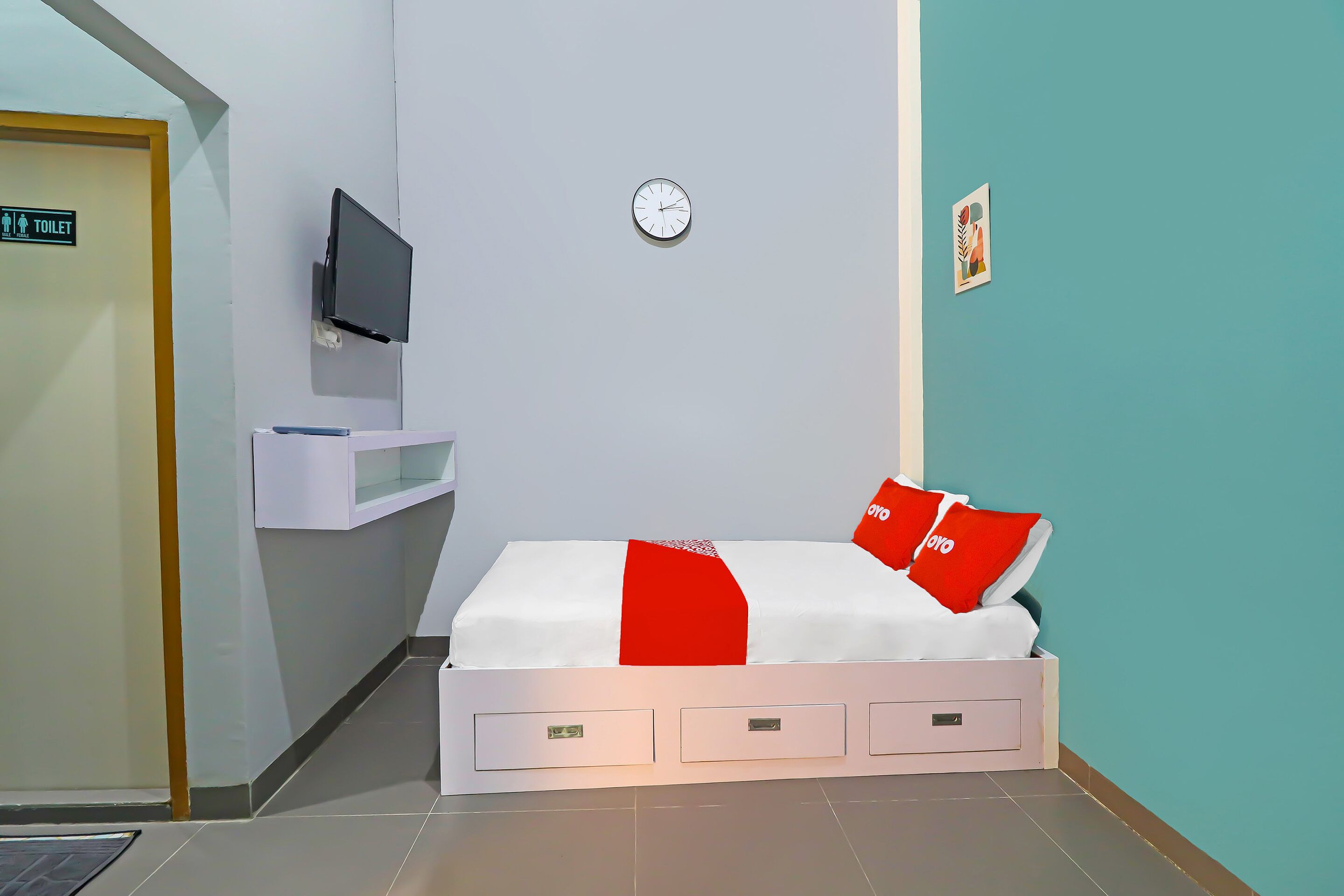 Ein Hotelzimmer mit Bett, Fernseher, einer Uhr und einem Schild mit der Aufschrift Toiletten.