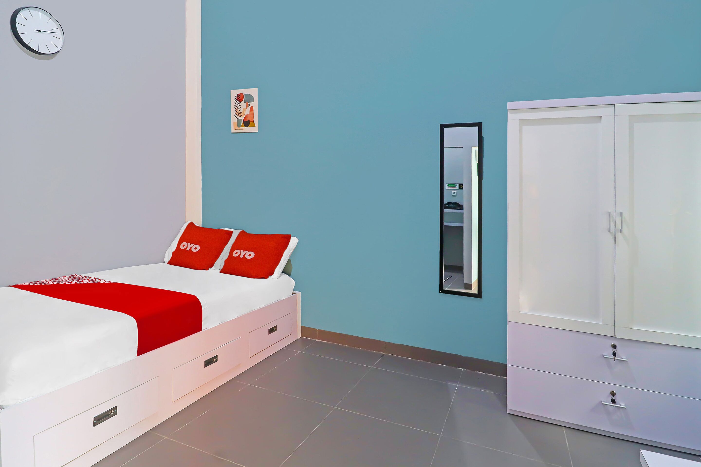 Ein Schlafzimmer mit Bett, Kleiderschrank, einer Uhr und einem gerahmten Bild an der Wand.