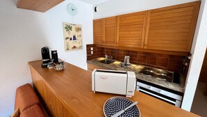 Eine kleine Küche mit Holzausstattung, einem eingebauten Backofen und einer Kaffeemaschine.