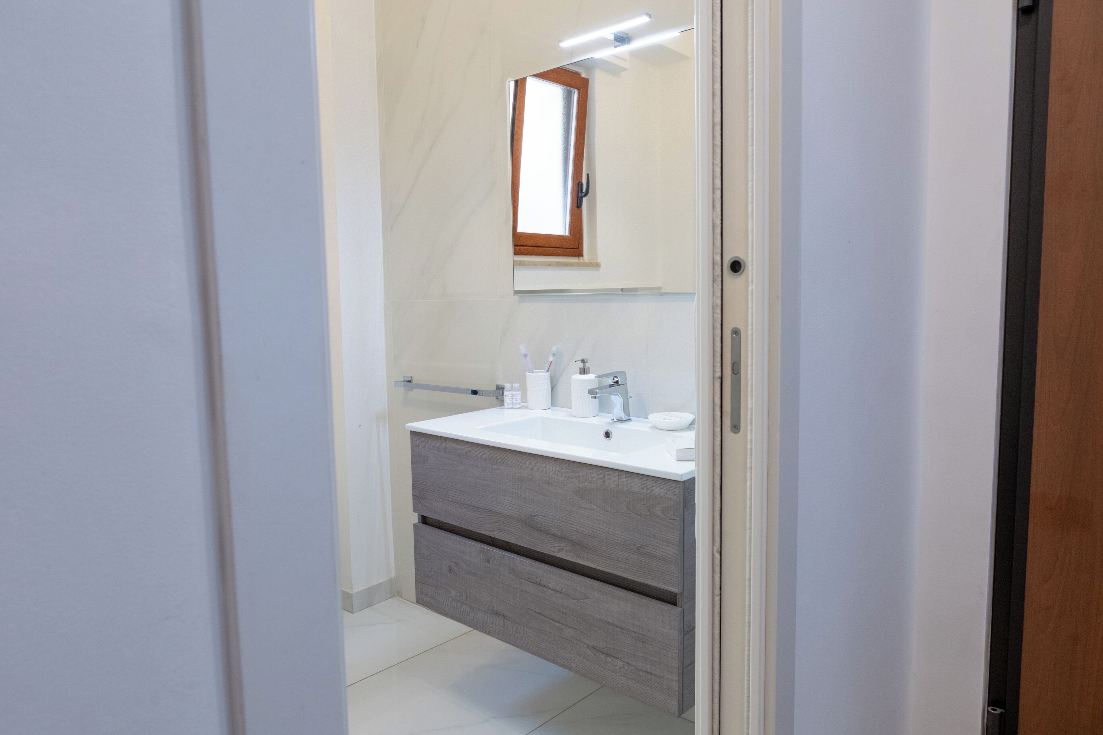 Ein Badezimmer mit einem weißen Waschbecken, einem Spiegel und einem Holzkabinent.
