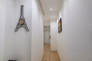 A hallway with a wall-mounted Eiffel Tower clock, a door at the end, and a framed picture on the right wall. - Residence D'azeglio (Palermo)