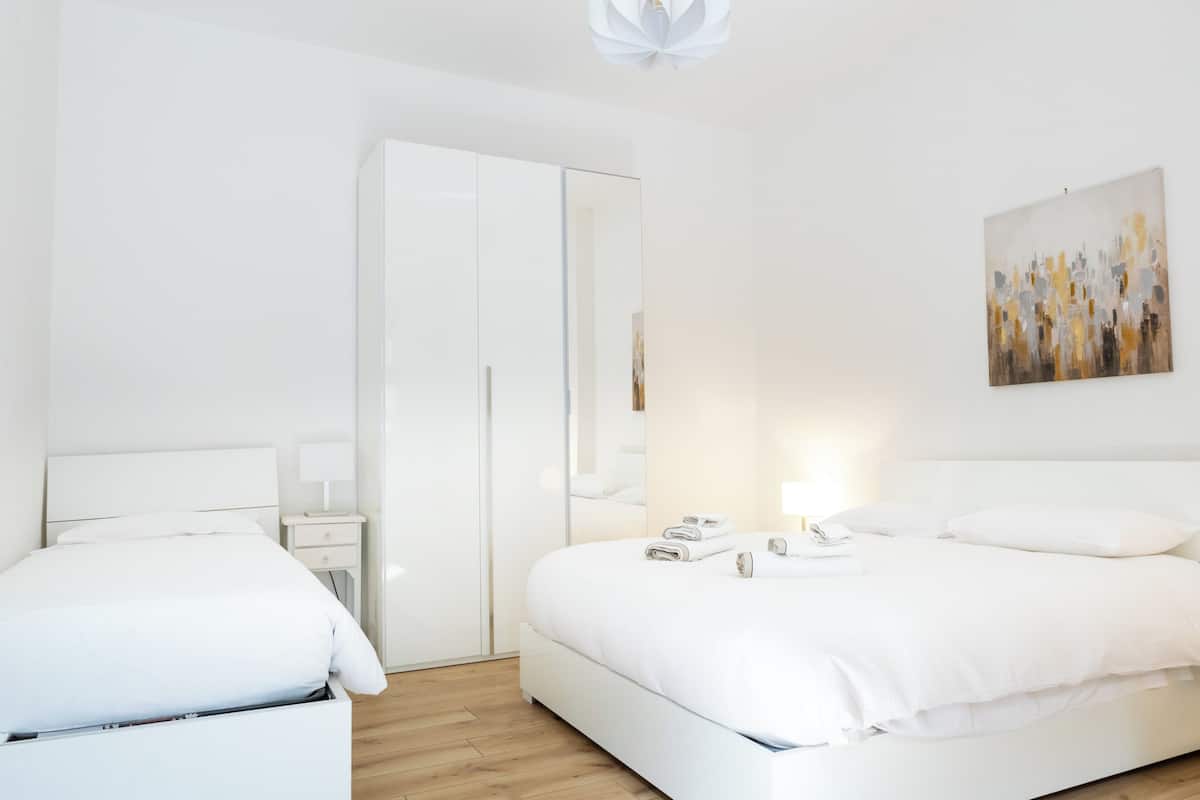 Un dormitorio moderno con una cama grande, una mesita de noche, un armario y una obra de arte en la pared.