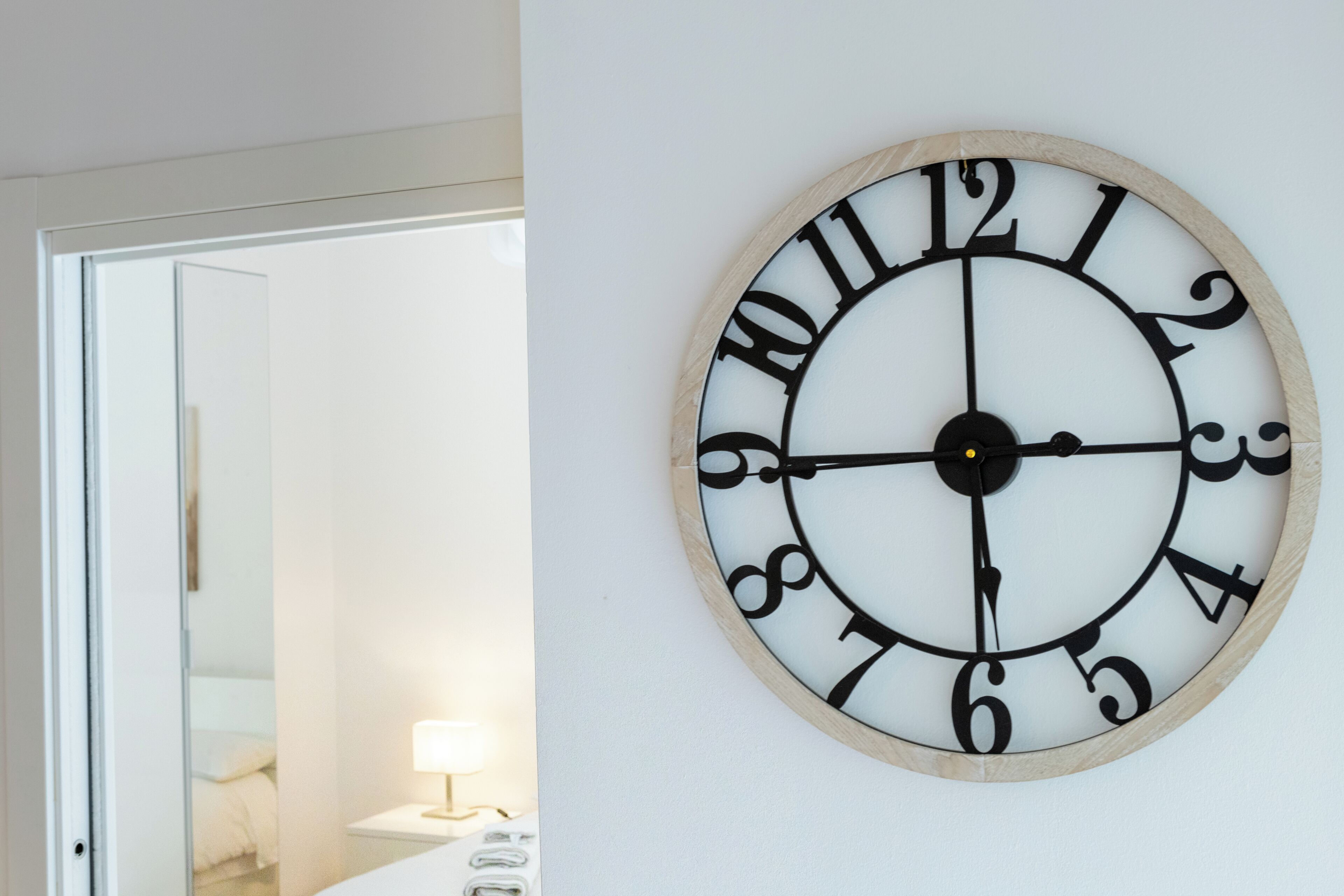 Een wandklok met houten lijst en zwarte cijfers.