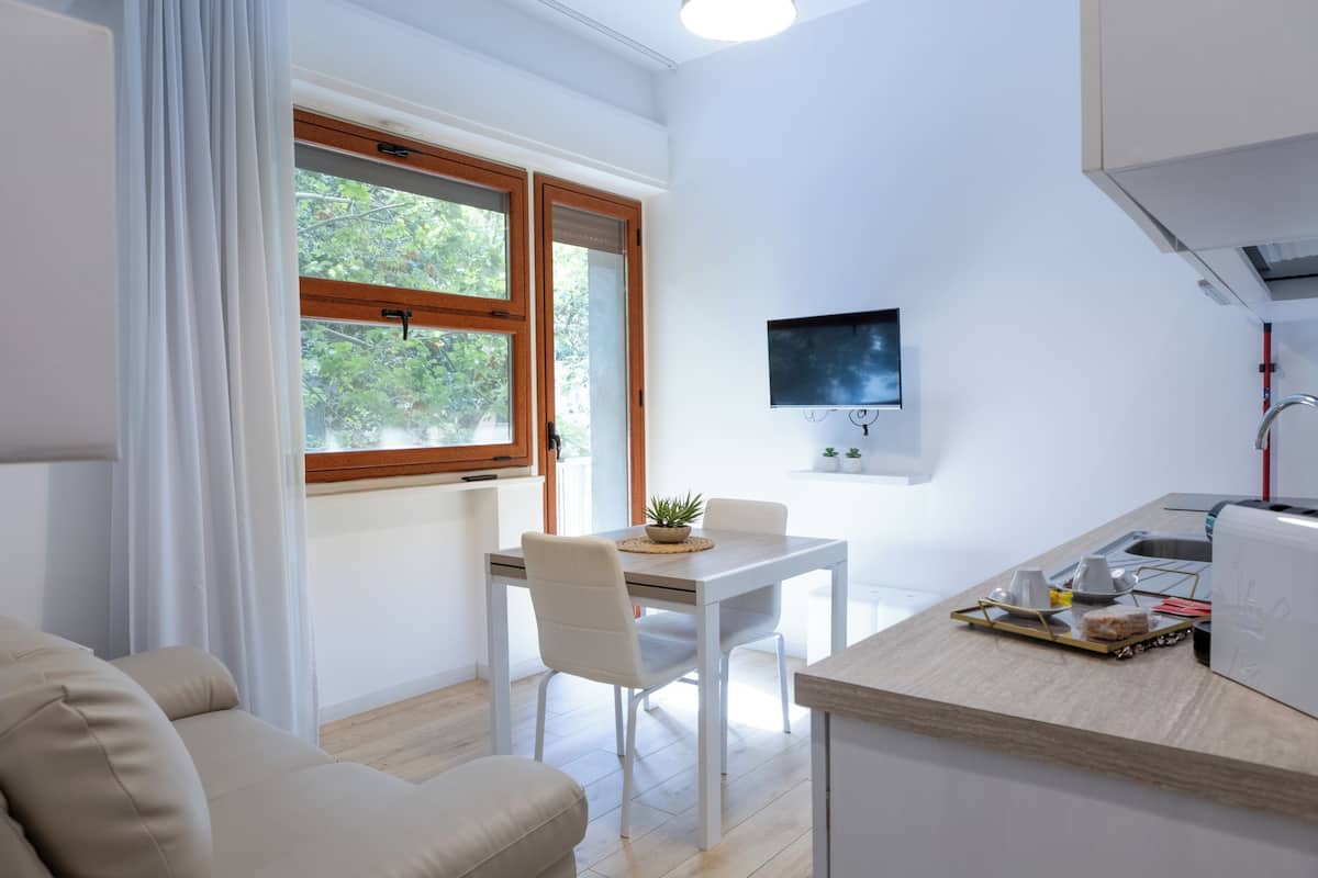 Una cocina moderna con comedor, televisor montado en la pared y ventana con cortinas.