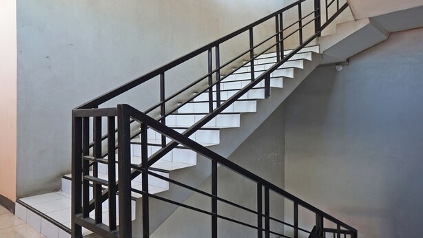 A staircase with a black metal railing and white steps. - OYO Life 92915 Duta Amnan Syariah (Sidoarjo)