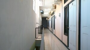 A long, narrow hallway with a tiled floor, black railings, and white doors on the right. - OYO Life 92915 Duta Amnan Syariah (Sidoarjo)