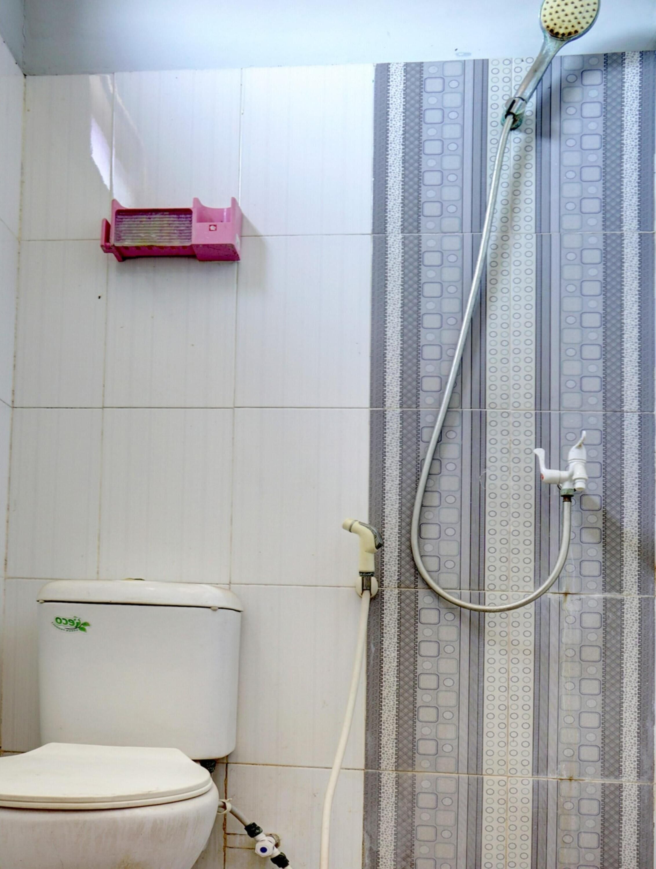 A bathroom with a toilet, a shower, and a patterned curtain.