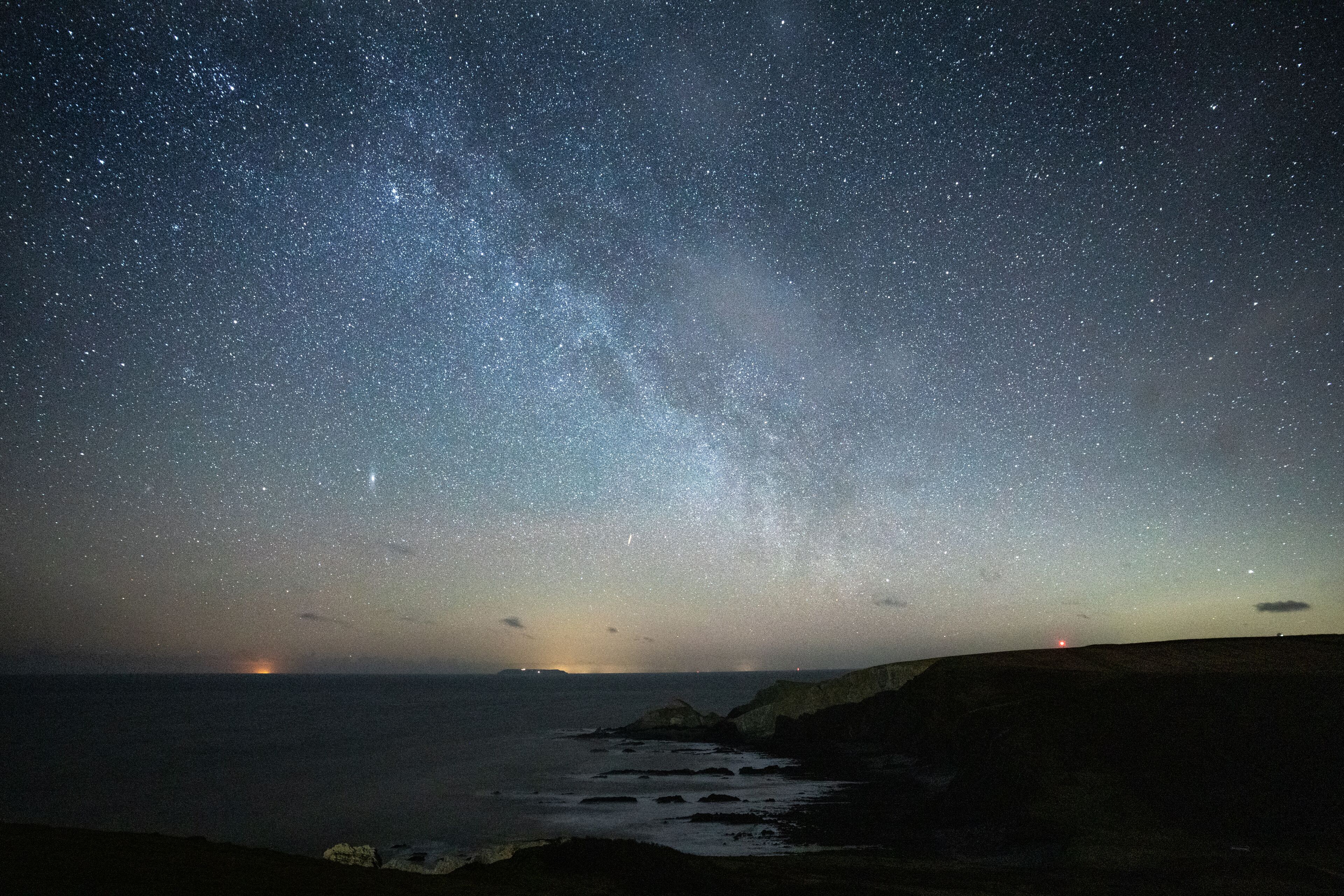 A starry night sky over a coastal landscape with a visible Milky Way.