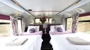 A train compartment with two beds, each with a pillow and a folded towel. - Fosfelle Glamping (Bideford)