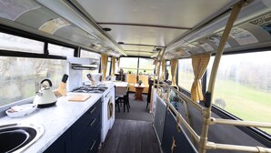 A compact kitchen with a sink, stove, and dining area. - Fosfelle Glamping (Bideford)