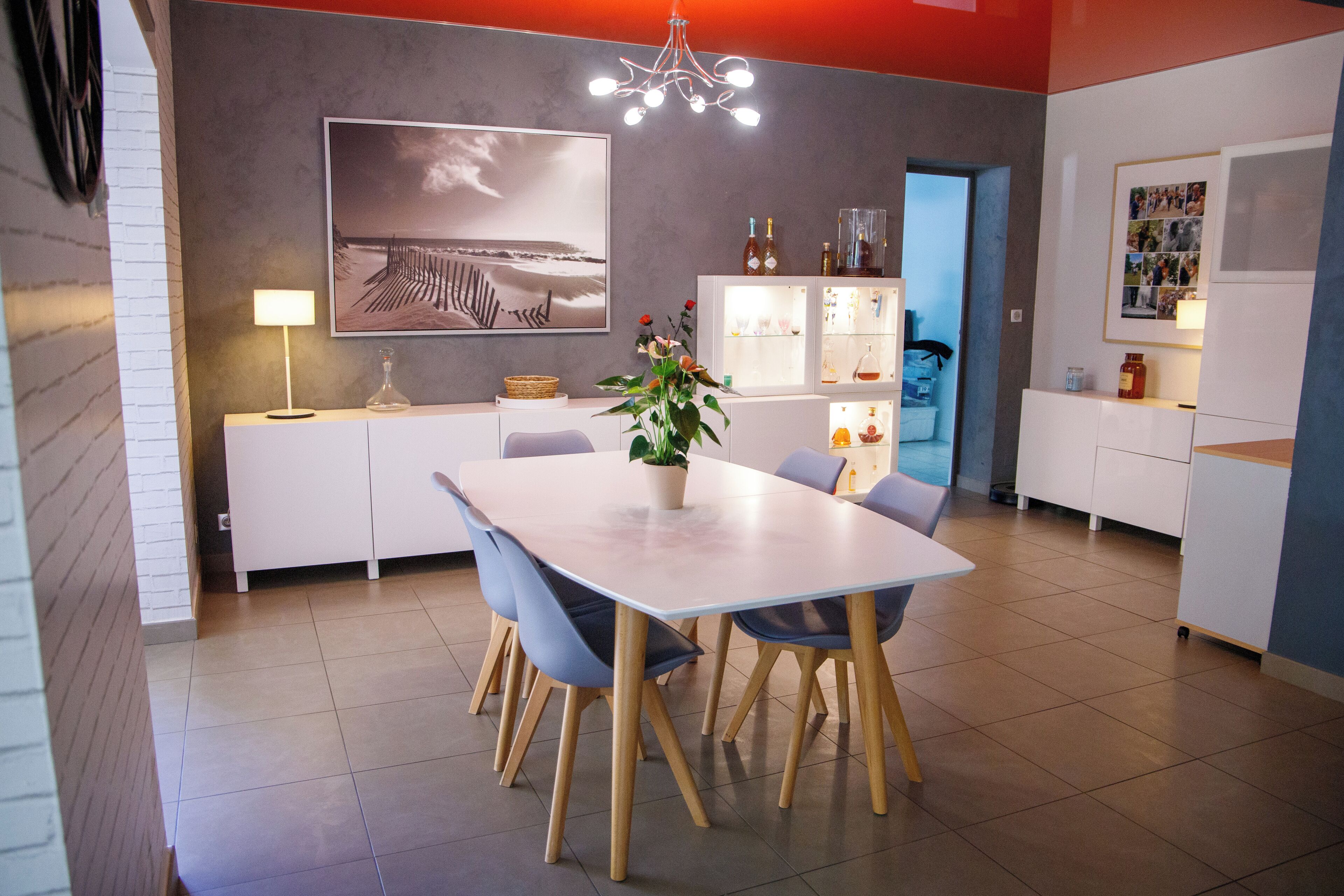 A modern dining area with a white table, blue chairs, and a potted plant.