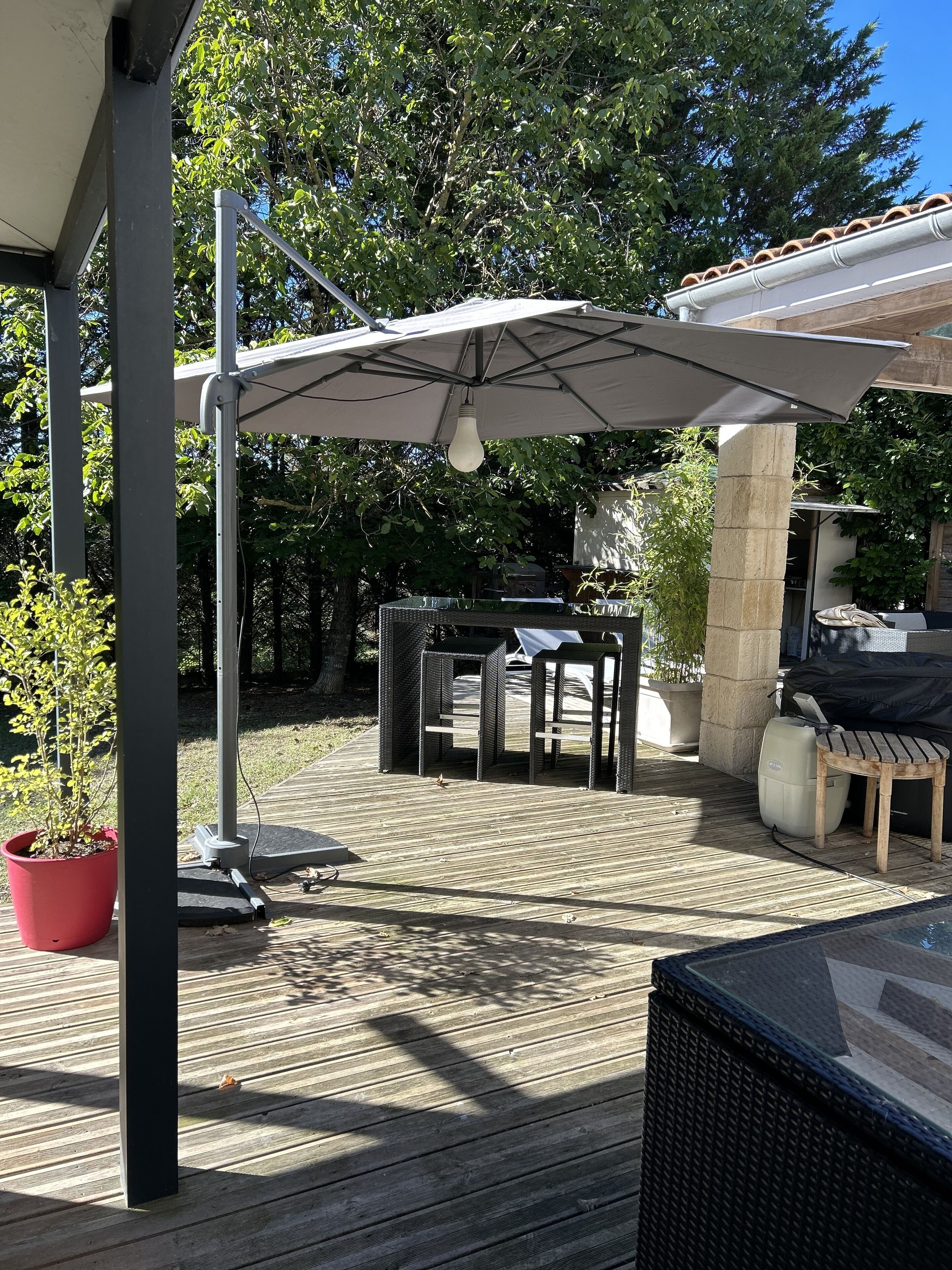 An outdoor patio area with a covered seating area, a table, and a potted plant.
